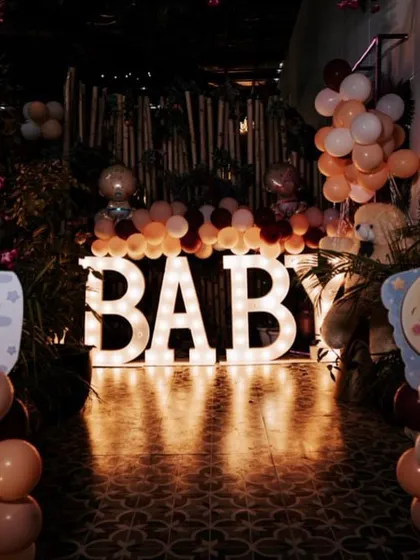 Marquee letters spelling "BABY" create a beautiful, softly lit focal point in this jungle-inspired baby shower setup.