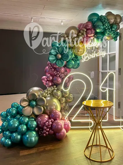 A stunning, iridescent balloon garland with a neon '21' sign, creating a modern and chic vibe for a milestone celebration.