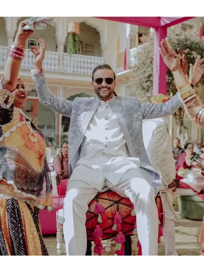 The groom makes a grand entrance on a dhol, surrounded by dancers, kicking off the wedding festivities with high energy.