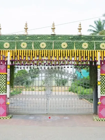 A grand and traditional entrance gate for a wedding. The gate is decorated with woven coconut leaves, marigolds, and banana stalks, creating an authentic and welcoming entrance for guests.