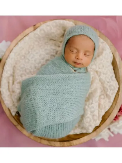 A closer look at our little dreamer. The texture of the knit swaddle and the soft background come together to create a truly serene image.