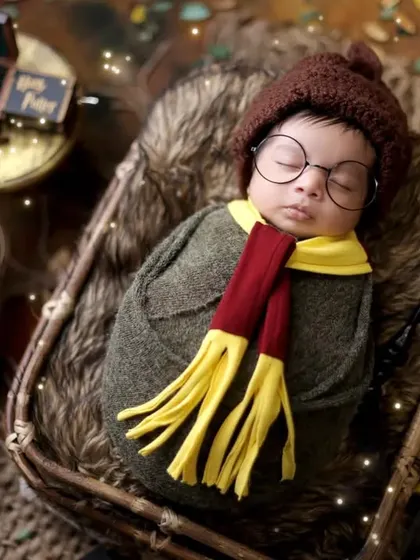 This overhead shot shows the newborn comfortably swaddled in a basket, surrounded by iconic Harry Potter props. We prioritize your baby's safety and comfort in every pose.
