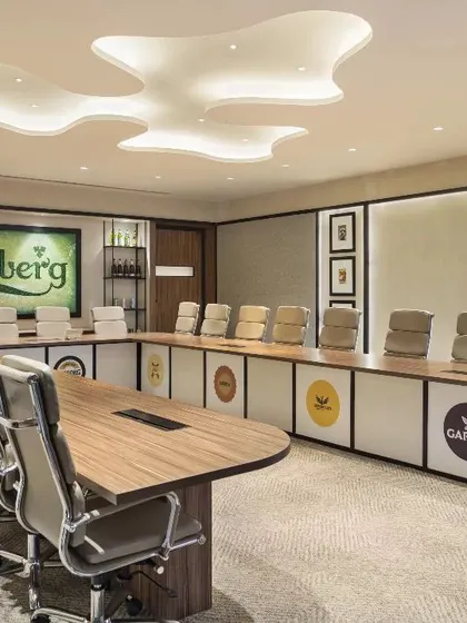 The main boardroom at the Carlsberg head office in Gurugram, a space that embodies brand legacy and sustainability. The design features a custom glass mosaic logo made from recycled Carlsberg bottles and a suspended hop symbol, translating corporate identity into a tangible, inspiring environment.