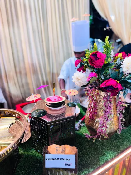 A chef preparing a bowl of watermelon ice cream at a beautifully decorated station.
