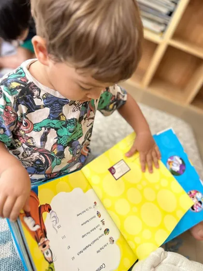 A child points to the pictures in a book, a form of "picture reading" that builds narrative skills and vocabulary before they can read words.