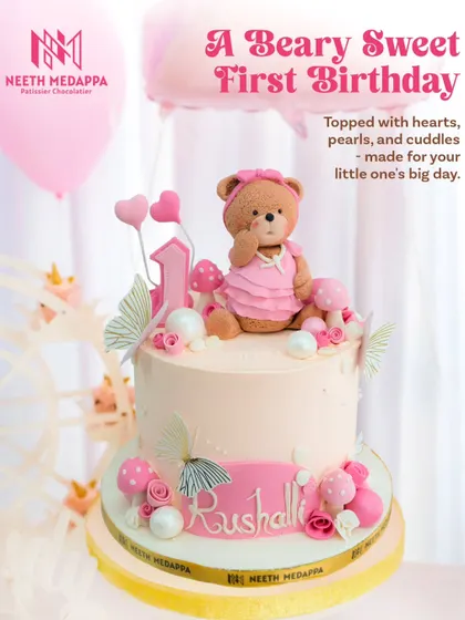 A beary sweet first birthday! This two-tiered cake features an adorable teddy bear in a pink dress, surrounded by mushrooms, butterflies, and pearls.