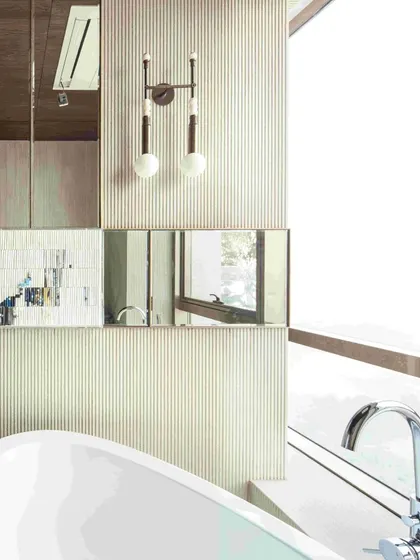 The sleek light fixtures and the partial view of the bathtub showcase the bathroom's modern and functional design, where every element is chosen for both style and utility.