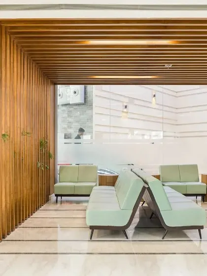 This waiting area uses wooden slats and indoor plants to create a biophilic and calming environment. The design offers a variety of seating options, providing flexibility for privacy and interaction.