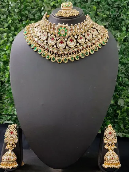 A classic red and green kundan choker set with matching jhumkas and maang tikka.