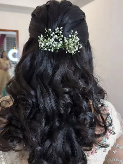 A half-up style with a bouffant and curls, accented with a cluster of baby's breath.