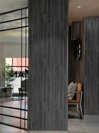 This detail shot shows the contrast between the smooth glass partition and the textured, dark wood-paneled walls. It's this interplay of materials that gives the office its modern and sophisticated character.