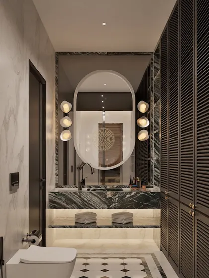 This bathroom and dressing area features dark louvered wardrobes and a vanity with a green marble countertop. The patterned floor tiles and oval mirror add layers of detail and texture.