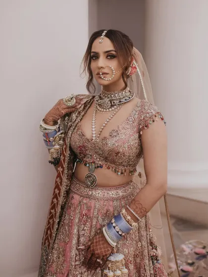 A powerful portrait of this modern bride. The makeup is bold yet balanced, with a strong focus on the eyes, complementing her unique jewelry and intricately embroidered lehenga.