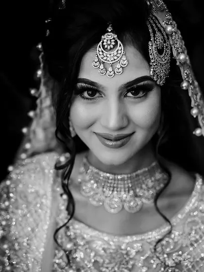 A stunning black and white portrait of a Muslim bride. The dramatic lighting and focus on her intricate jewelry and expressive eyes create a look of timeless glamour.