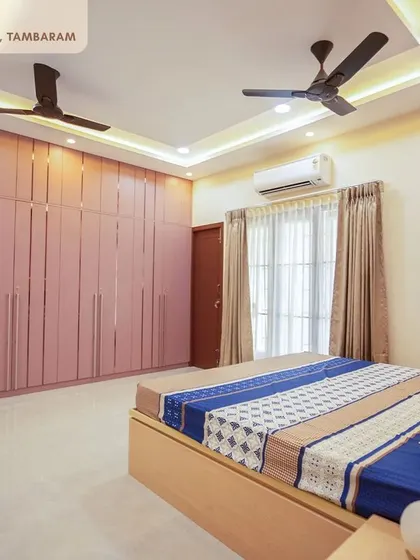 A bedroom in the Tambaram villa with floor-to-ceiling wardrobes in a soft pink, featuring a fluted design that adds texture and elegance to the space.