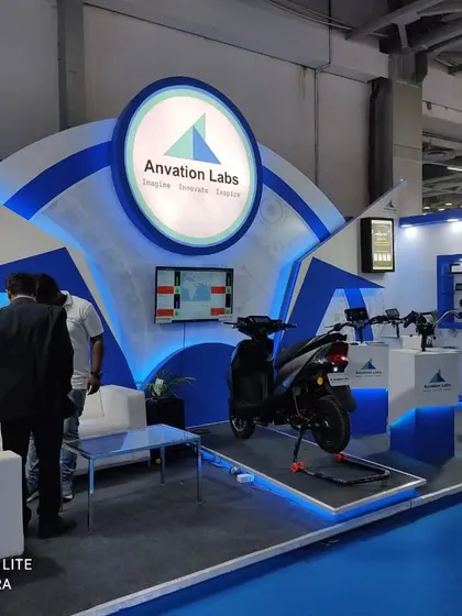 A sleek and modern stall design for Anvation Labs, featuring product display podiums and a comfortable seating area for client meetings.