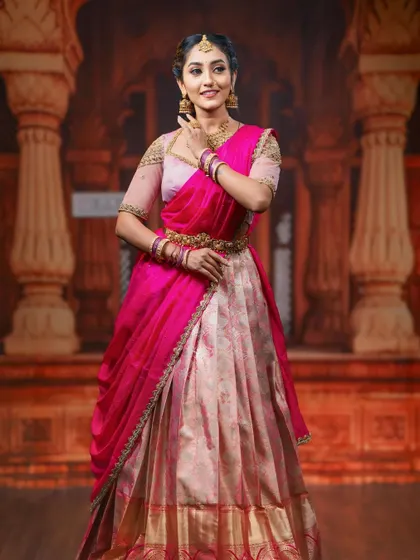 A graceful pose showing the flow of the half saree's dupatta and the intricate design of our peacock-themed vaddanam.