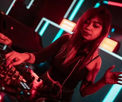 A moment of connection with the music. The red lighting adds to the intensity of the set, creating a fiery atmosphere on the dance floor.