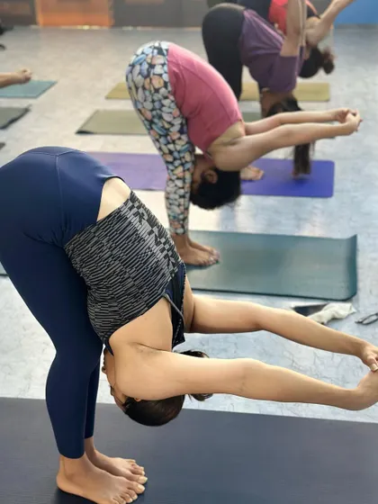 Students in a deep forward fold with hands clasped behind the back, opening up the shoulders.