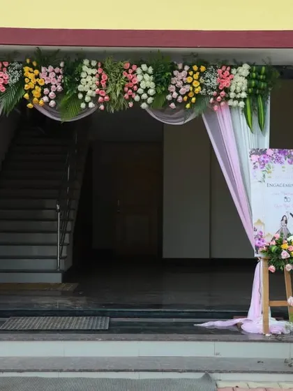 The entrance decor for an engagement ceremony, featuring a floral arch and a personalized welcome sign.