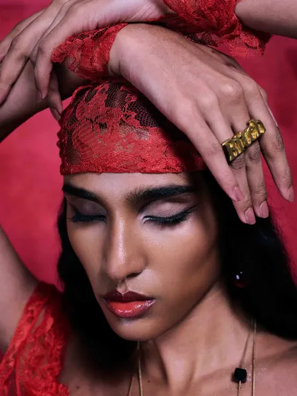 Published in Flanelle Magazine, this image uses a bold, monochromatic red theme. The focus is on the custom gold 'Brat' ring, with the model's pose and the lace headband adding layers of texture and attitude to this high-fashion accessory portrait.