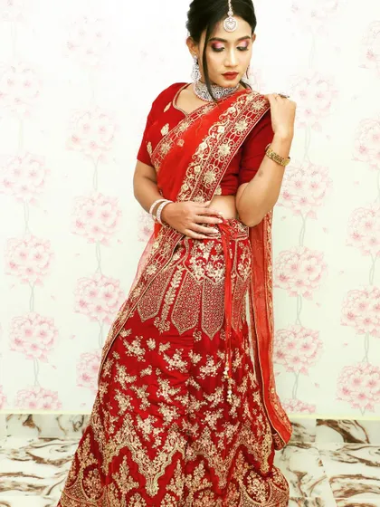 A full-length view of a maroon velvet lehenga available for rent. The skirt has extensive gold threadwork, making it a grand choice for any bride.