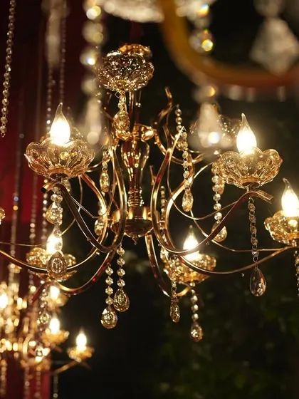 A detailed shot of a crystal and gold chandelier, one of many that illuminated the royal red reception.