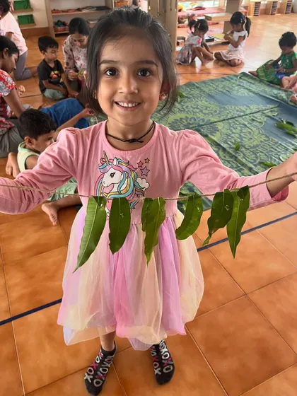 This happy girl shows off the leaf garland she made. The sense of accomplishment from creating something with her own hands is invaluable.