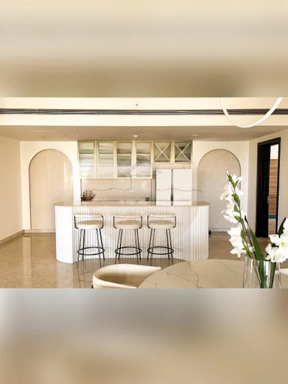 This home features a stunning open-plan kitchen with a fluted bar counter and a custom wine rack. The design uses arches and a clean white palette to create a space that is perfect for entertaining.