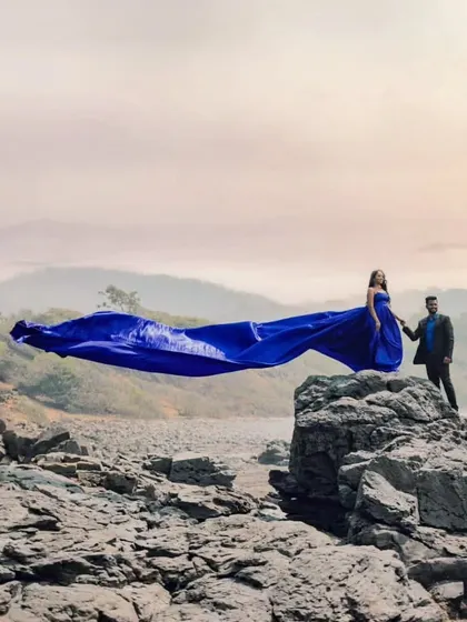 The royal blue gown stands out against the rugged, rocky landscape. This is a perfect choice for couples who want a bold color for their adventure pre-wedding session.