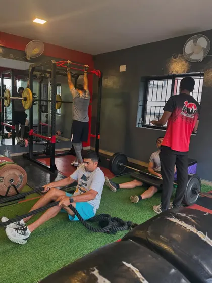 A snapshot of the gym floor in action. One client does pull-ups, another does rope pulls, while others rest. This shows the circuit-style training we often employ.