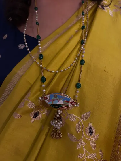 The joy of reviving heirlooms is unparalleled. We transformed a vintage 'kamarband' (waist belt) into a stunning hand-painted pendant, pairing it with another heirloom mala for a look that is rich in history.