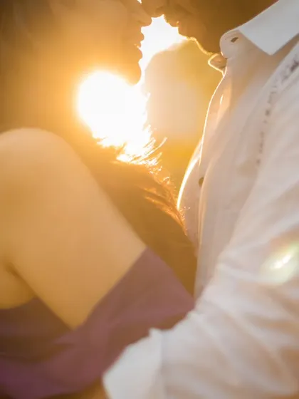 A romantic, sun-flared pre-wedding portrait. The warm light creates a beautiful halo effect, adding a touch of magic to this intimate moment.