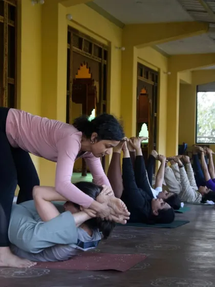 Assisting a student in a deep forward fold. My retreats are a time for personalized attention, helping each person explore their practice in a safe and supportive way.