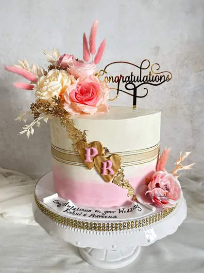 Love in full bloom. A post-wedding congratulatory cake with a beautiful pink ombre effect, gold stripes, and a cascade of florals.