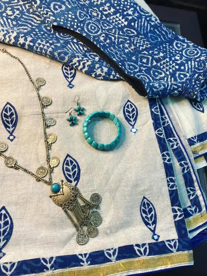 A flat-lay for Day 1 of Navratri. A white pure cotton saree with applique work, paired with an indigo blouse and silver tribal jewellery.