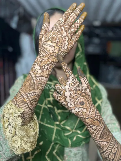 A full view of an engagement mehendi, extending from the palms to the elbows. The bride's pose shows off the beautiful, continuous design.