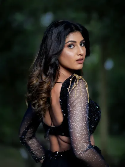 A back view of the model, showing the details of her sequined top and her elegant posture.