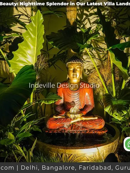 A close-up of the spotlit Buddha water feature, nestled amongst lush foliage. This is the serene heart of the garden at night.