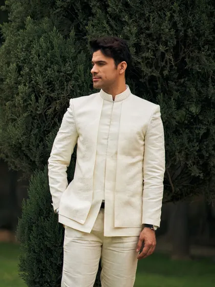 This ivory Jodhpuri suit features a unique layered placket design, adding a modern architectural element to a traditional silhouette. It's handcrafted in my atelier for those who appreciate subtle yet impactful design details.