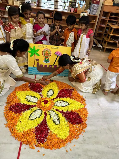 A teacher shows a child how to add the final touches to the pookalam, a moment of focused, shared creation.