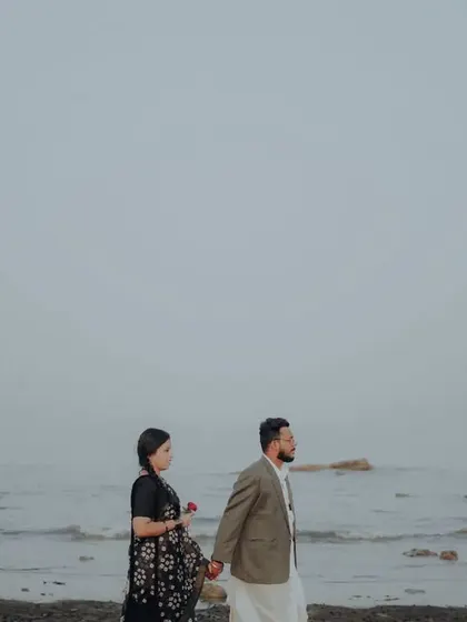 A minimalist wide shot of the couple walking on the beach, emphasizing the peaceful and expansive scenery.