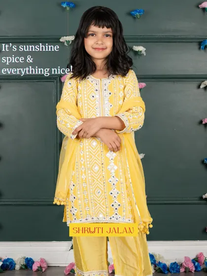 It's sunshine, spice, and everything nice. This little girl is wearing my yellow mirror-work sharara set, a bright and cheerful outfit that’s perfect for any daytime celebration.