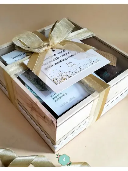 A beautiful wedding hamper designed for relaxation and rejuvenation. It includes wine glasses, a face mask, a scented candle, and a silk eye mask, all packed in a rustic wooden crate.