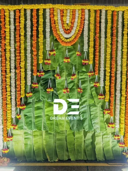 This traditional naming ceremony backdrop is made entirely of fresh banana leaves and marigold garlands. The Little Krishna cutouts add a playful and divine touch to the authentic South Indian decor.