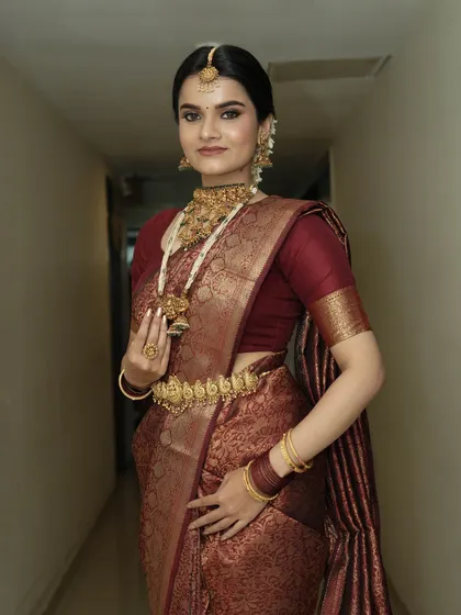 A full-length view of this perfected South Indian glam. The makeup is the perfect complement to her stunning saree and jewelry.