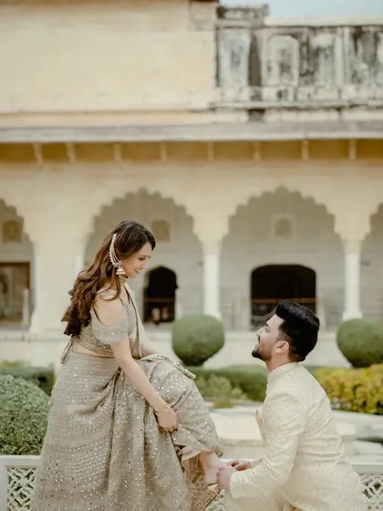 A classic, chivalrous moment in the gardens of a Jaipur palace. This pose is timeless and romantic, perfectly fitting the royal theme of the location.