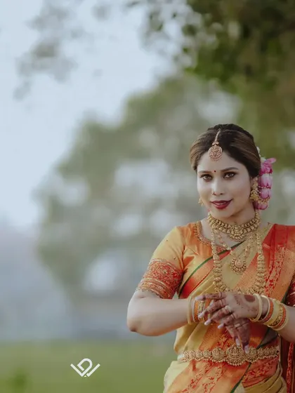 A bride stands in a green field, her traditional attire contrasting beautifully with the natural setting.