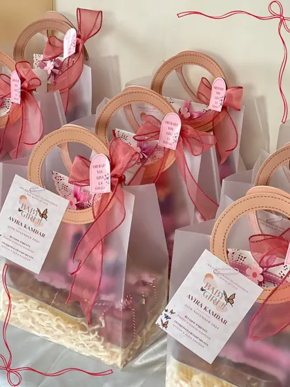 These elegant semi-transparent bags with ring handles were perfect for the baby girl announcement gifts. Each one is tied with a ribbon and a custom tag.