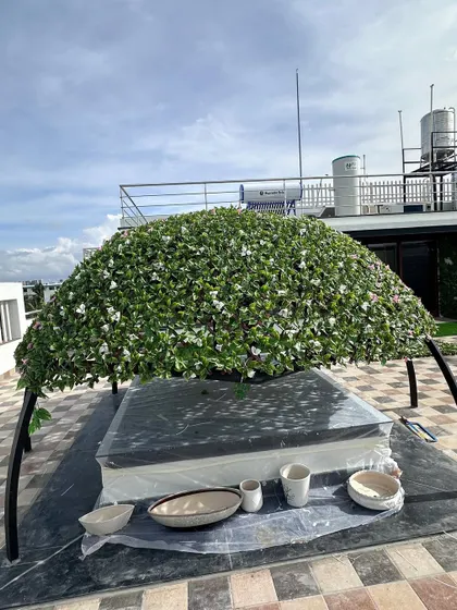 Another angle of the rooftop gazebo during installation. You can see the sturdy frame and the dense application of the artificial foliage, designed to withstand outdoor conditions.